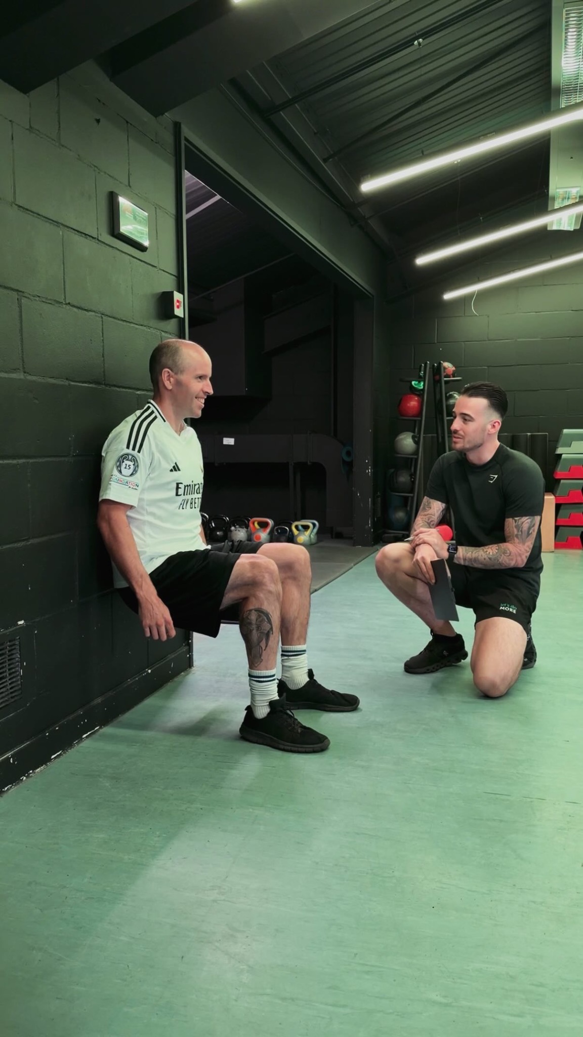 Joe Angelo assessing a client during a wall-sit fitness assessment at Putlands Gym